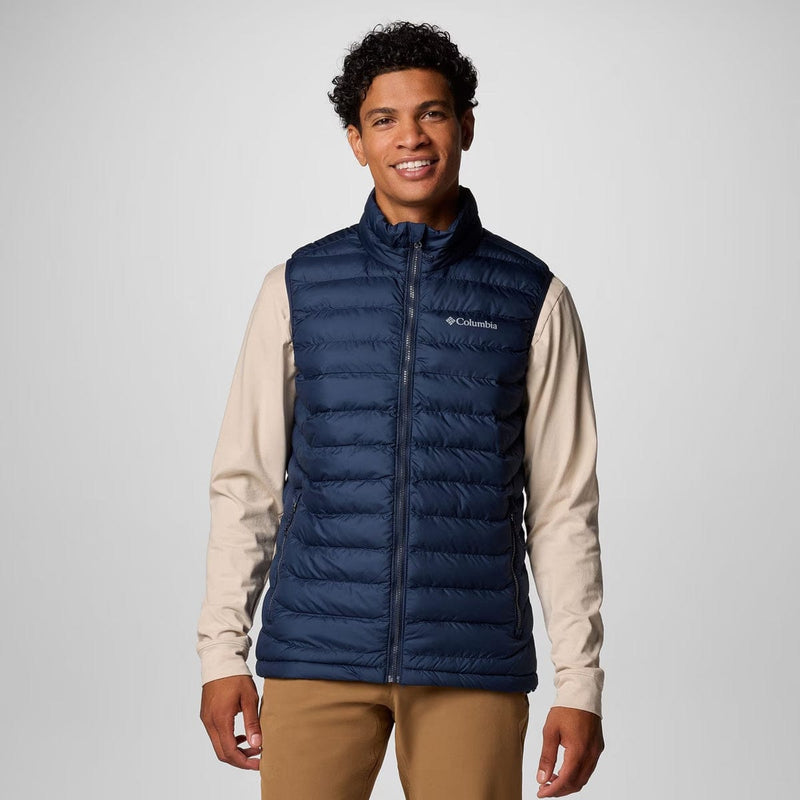 Load image into Gallery viewer, Man wearing a blue puffer vest with Columbia logo on a light gray background

