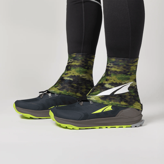 Black and green camouflage shoe covers with a brand logo on a light gray background