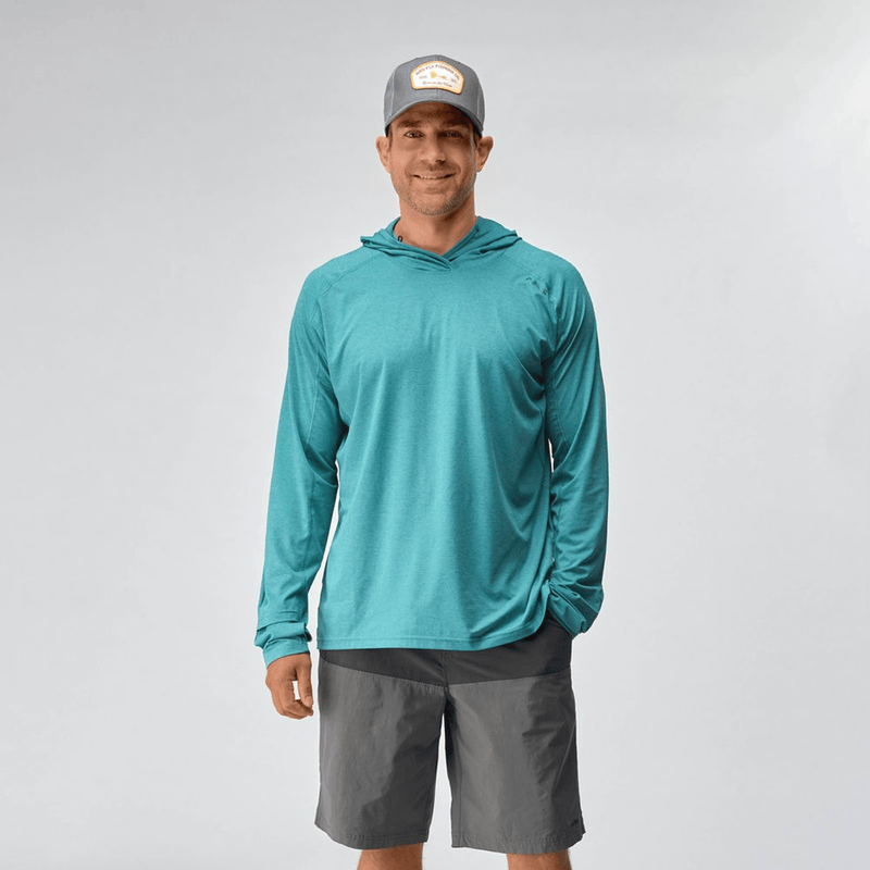 Load image into Gallery viewer, Man wearing a teal long-sleeve shirt, gray shorts, and a cap on a light gray background

