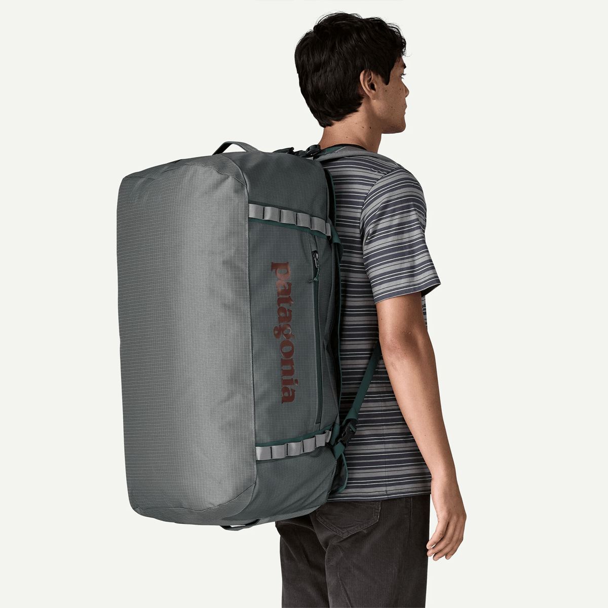 Person wearing a large gray backpack with Patagonia logo on a white background