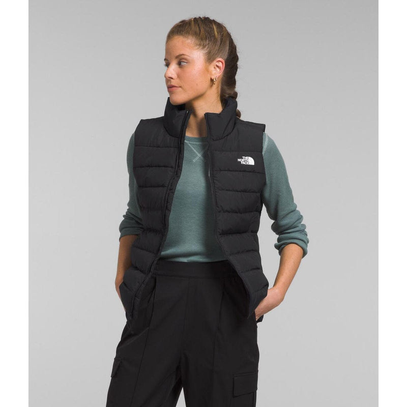 Load image into Gallery viewer, Person wearing a black puffer vest with a logo on a gray background

