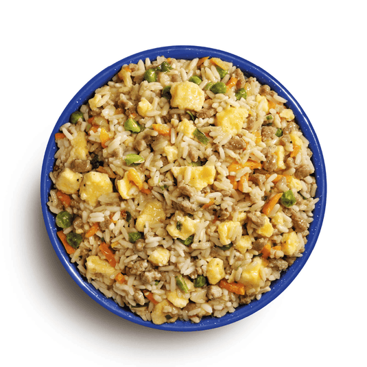 Bowl of fried rice with vegetables and meat on a white background