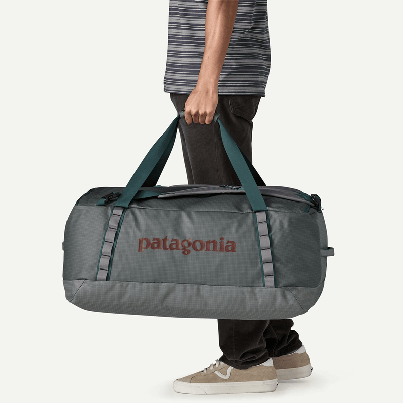 Load image into Gallery viewer, Person holding a Patagonia duffel bag on a white background
