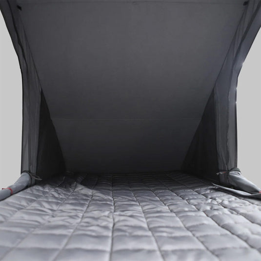 Gray quilted mattress with a dark gray tent-like structure on a light gray background