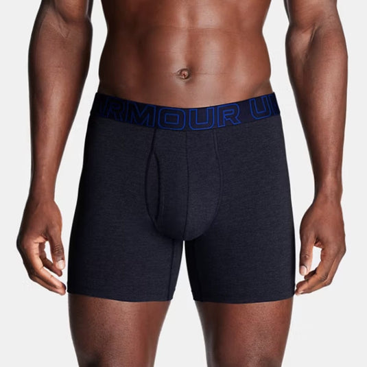 Man wearing navy boxer briefs with blue waistband on a light gray background