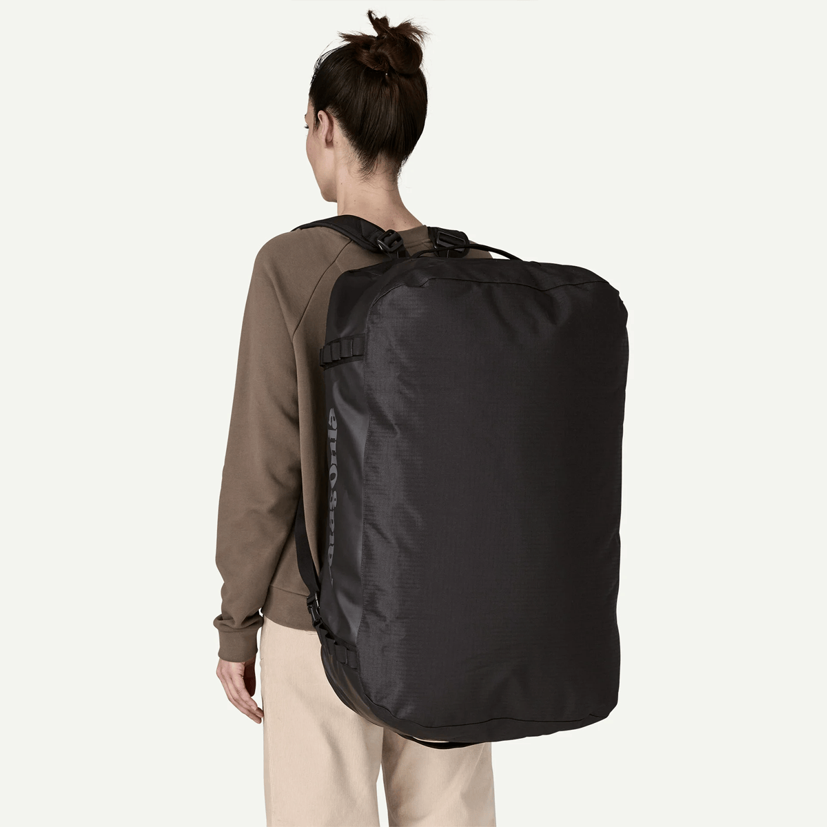 Person wearing a large black backpack on a white background