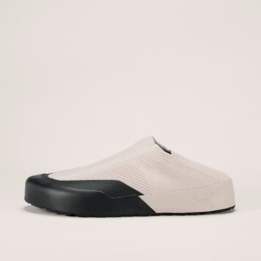 White slip-on shoe with black sole on a light beige background