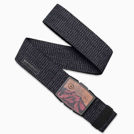 A black stretch belt with a wooden buckle featuring a mountain design, laid out on a white background.