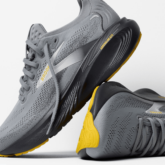 Gray running shoes with yellow accents on a light gray background