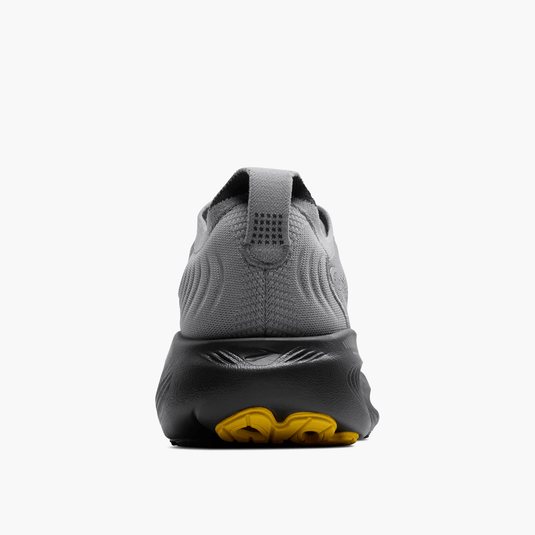 Gray athletic shoe with yellow sole on a white background